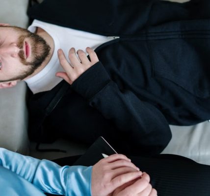 A man lying on a couch during a therapy session with a counselor in a modern office setting.